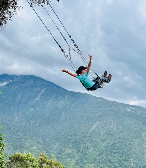 A person on a swing with a breathtaking mountain view.