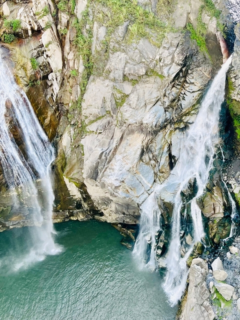 Cascading waterfalls over rocky cliffs into a pool.