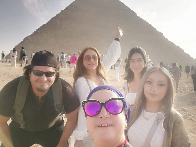       Group of people posing with the Great Pyramid in the background.
  