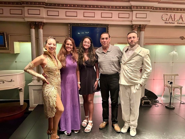       Group of people posing in an interior setting with performers.
  