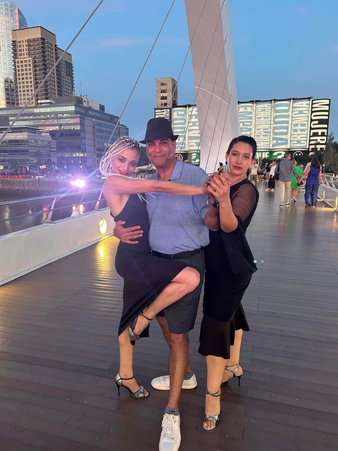       Man posing with tango dancers on a bridge.
  