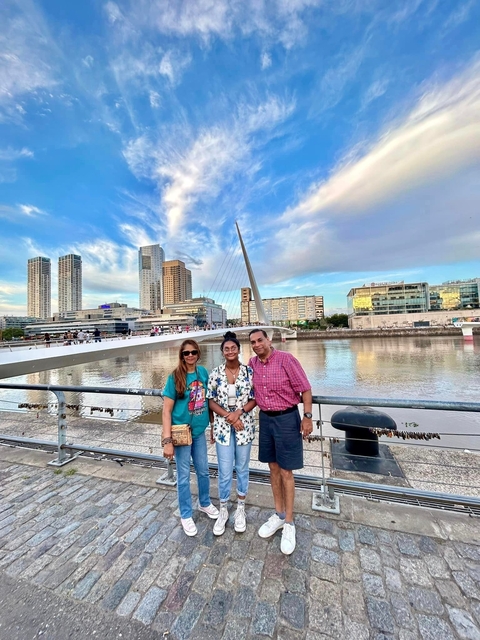       Family posing by a modern urban bridge with skyline.
  