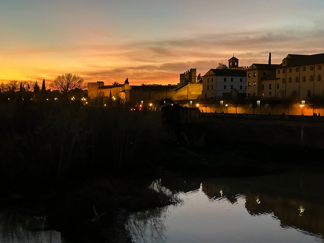 Historical building by a river at sunset.