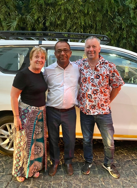       Three people posing in front of a vehicle.
  