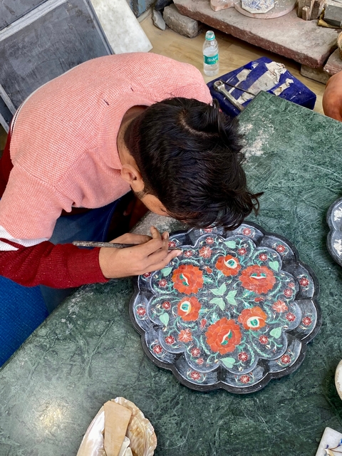       Close-up of a person crafting a decorative floral pattern.
  