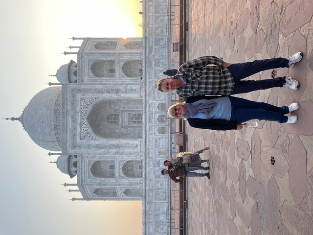       Two people standing in front of the Taj Mahal.
  