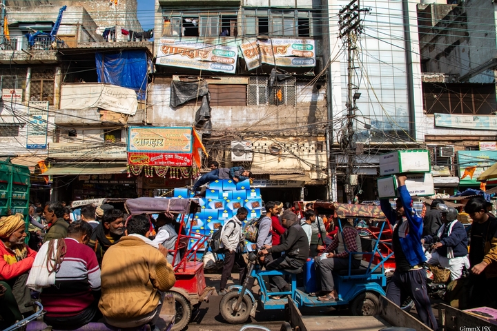 Busy street scene with rickshaws and people in an urban setting.