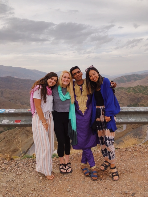       A group of people posing in front of a mountainous landscape.
  