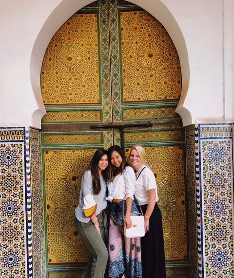       Three women posing in front of an ornate doorway.
  