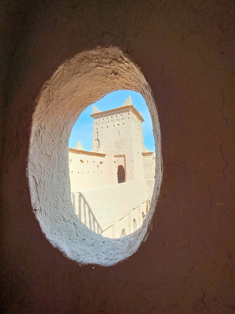       A view through a circular window in a mud structure.
  