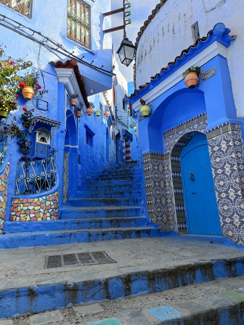       Blue alleyway in Chefchaouen with tiled steps and decorative walls.
  