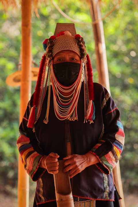      Person in traditional colorful attire with beaded headdress
  