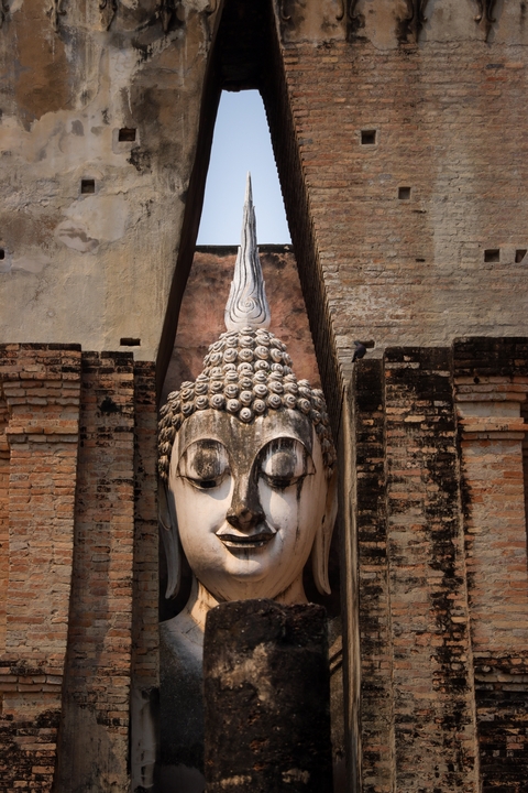       Large Buddha face embedded in ancient brick temple wall
  