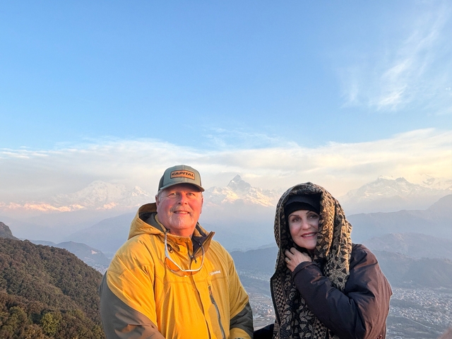 Two people posing against a mountain backdrop during sunset.