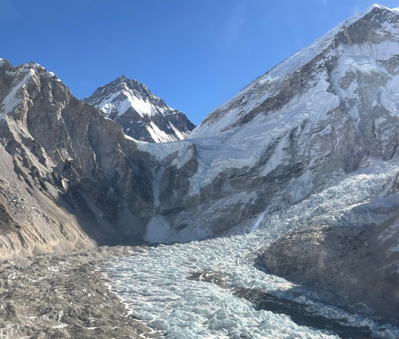 Glacier landscape with towering mountains in the background.