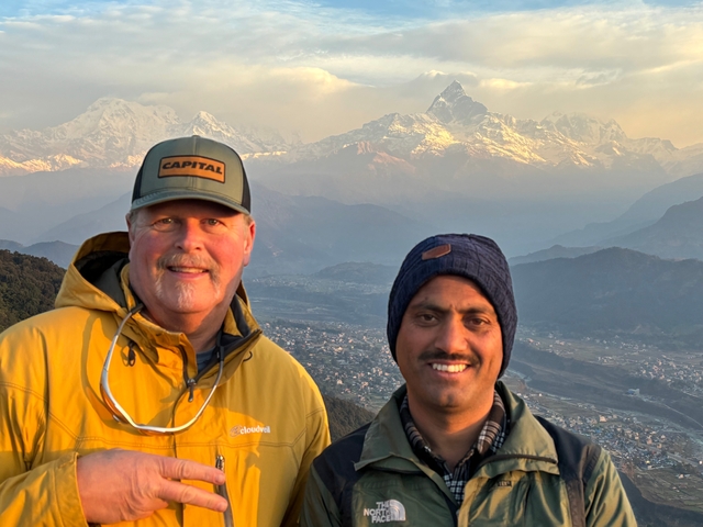 Two people posing with mountains in the background.