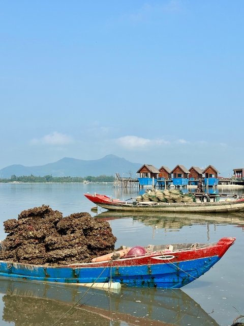 Fishing village with boats on the water and hills in the background.