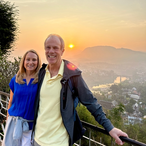 Couple posing with a sunset and landscape in the background.