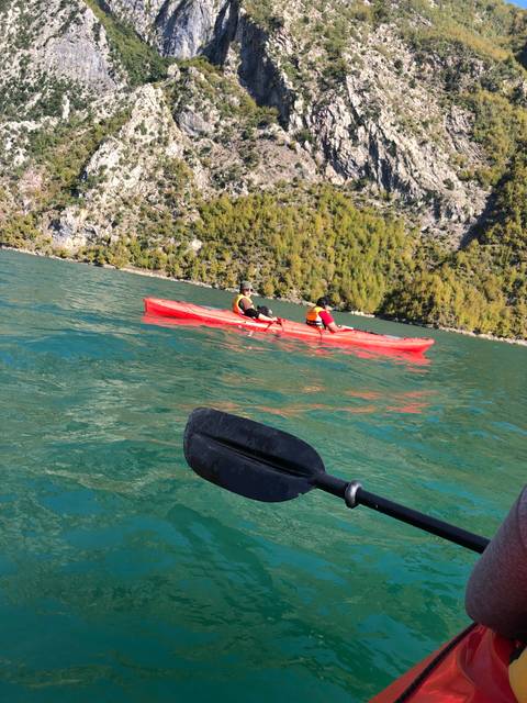 People kayaking in a lake near steep cliffs.