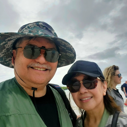 Close-up of a man and woman's faces, smiling at the camera.
