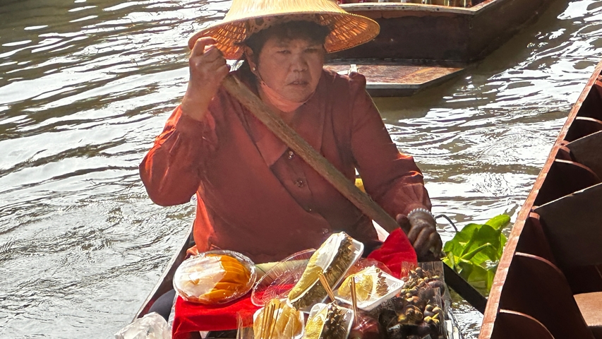 Woman selling food from a boat in a floating market.