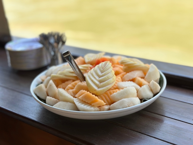 Plate of assorted tropical fruit pieces on a wooden table.