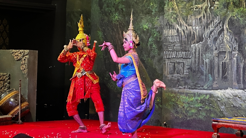 Traditional dancers in elaborate costumes performing on stage.
