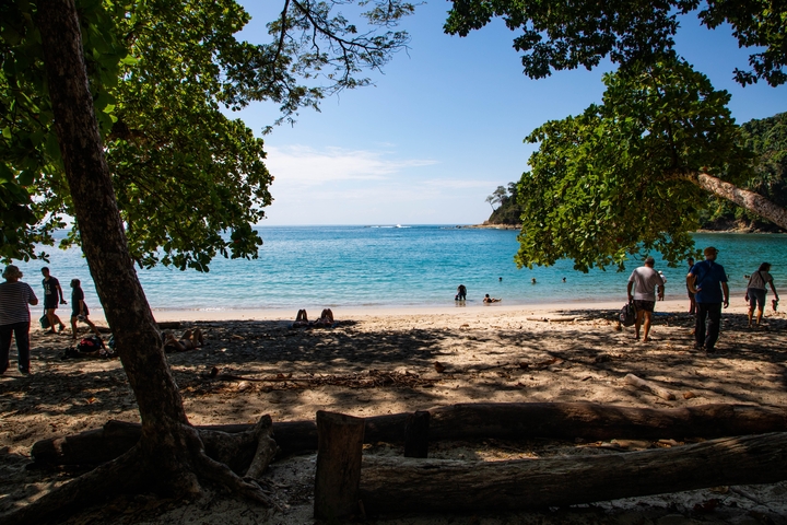 Beach scene with clear waters and people enjoying the sun.