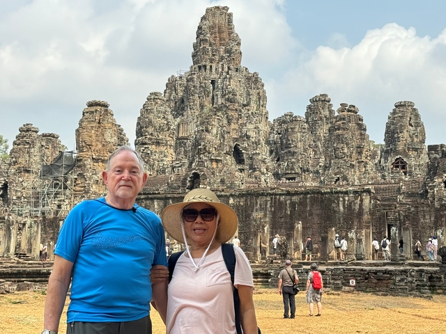       Tourists posing in front of an ancient temple complex.
  