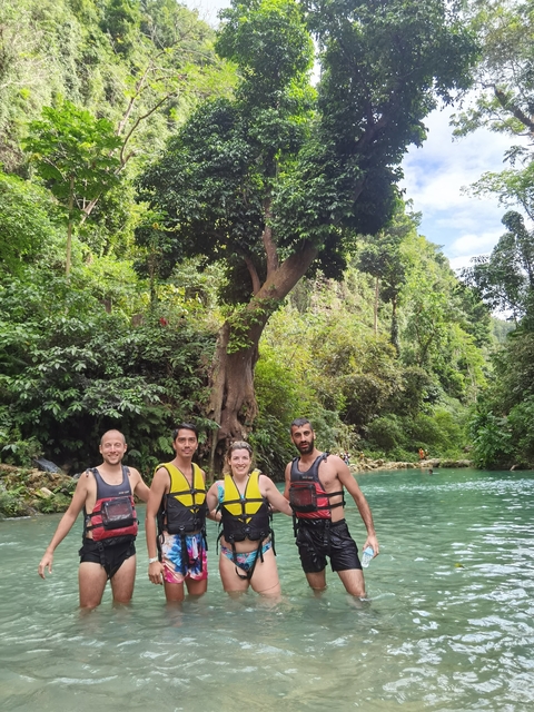      Group of people in life jackets by a jungle river.
  