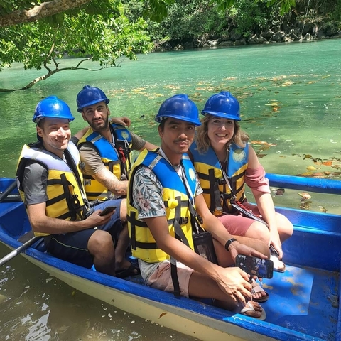       Group wearing helmets and vests in a boat on a river.
  