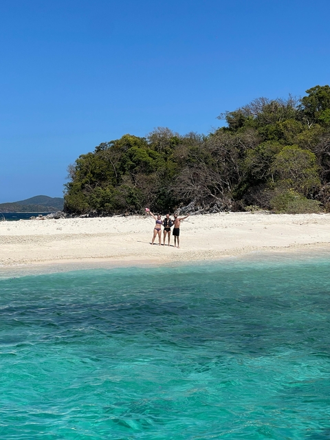       Three people waving on a sandy beach.
  