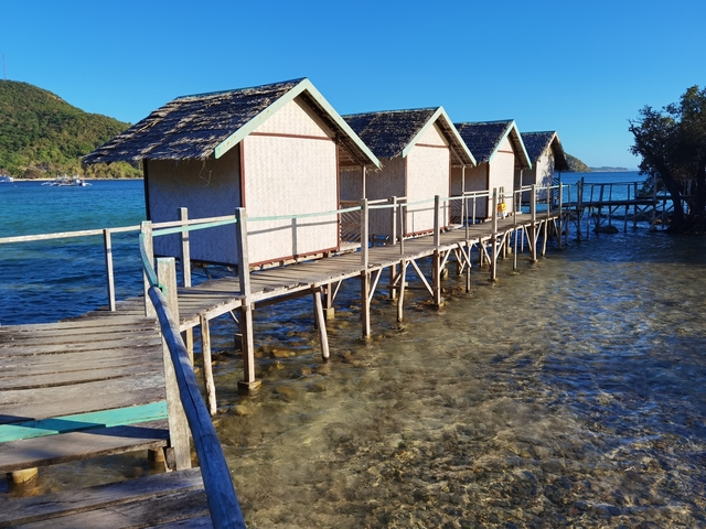       Rustic beach huts over clear, shallow water.
  