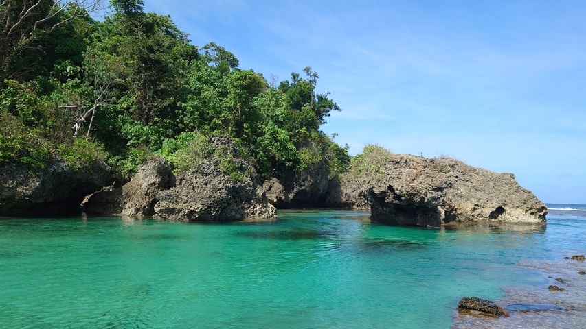 Turquoise water with lush rock formations.