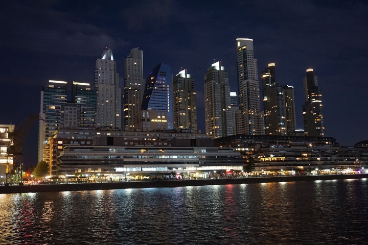 Modern city skyline at night reflecting in water.