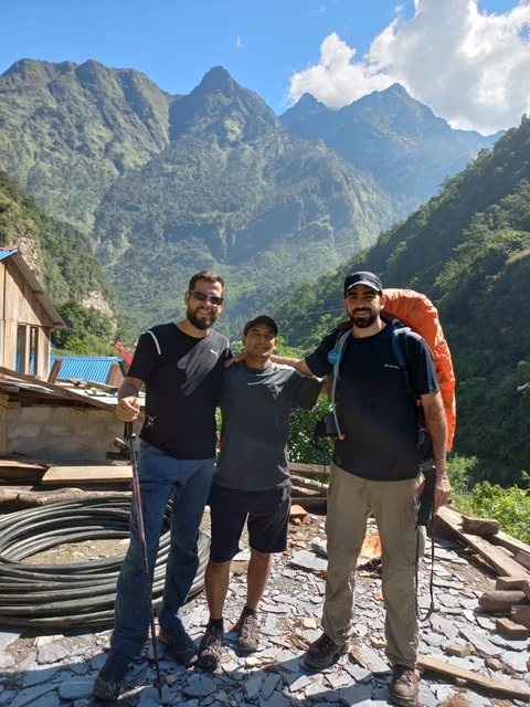       Three hikers posing in a mountain village.
  