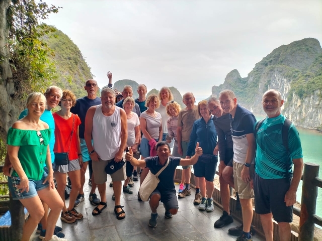 A group photo of tourists with Halong Bay in the background.