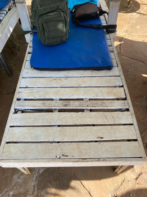       Wooden pallet with blue cushion on the floor.
  