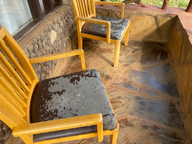       Wooden chairs with worn-out surfaces on a stone floor.
  