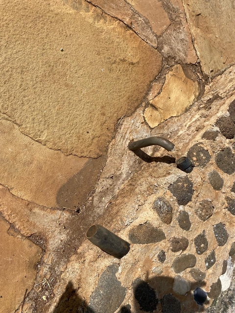       Broken faucet on an uneven stone surface.
  