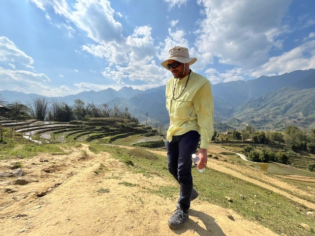       A person exploring terraced rice fields under a bright sky.
  