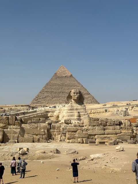       The Sphinx and Pyramid of Giza with tourists around.
  