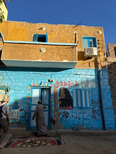 Street mural with people near a painted blue building.