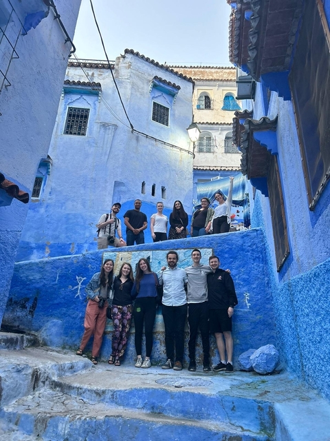       Group of people posing in a blue alleyway.
  