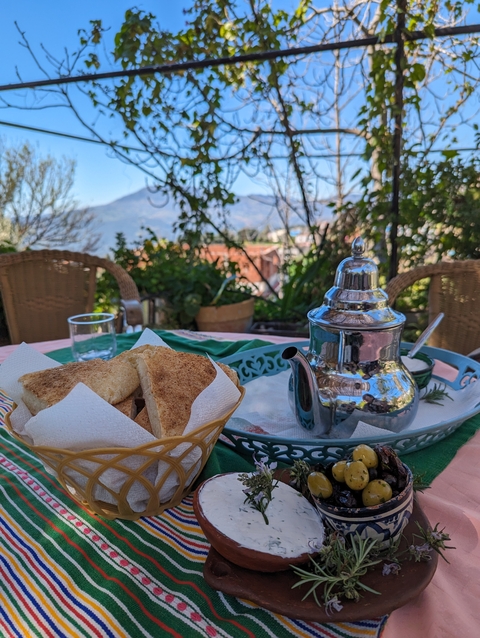       Breakfast table with tea and bread with mountain view.
  