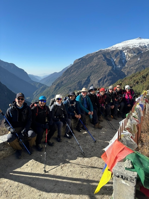       Trekking group with backdrop of mountains and prayer flags.
  