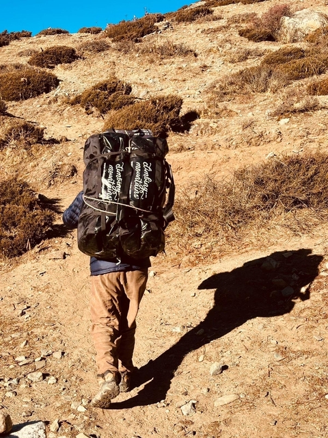       Person carrying a heavy backpack uphill.
  