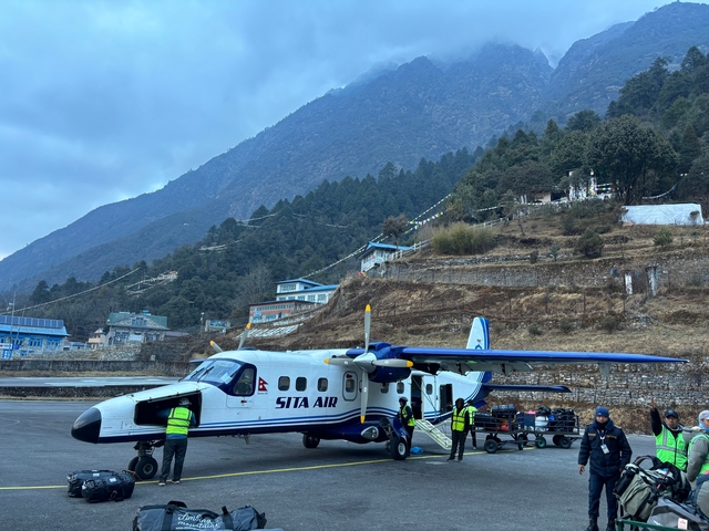       Small airplane parked with mountainous backdrop.
  