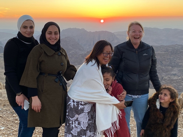 A group of people on a mountain at sunset enjoying the view