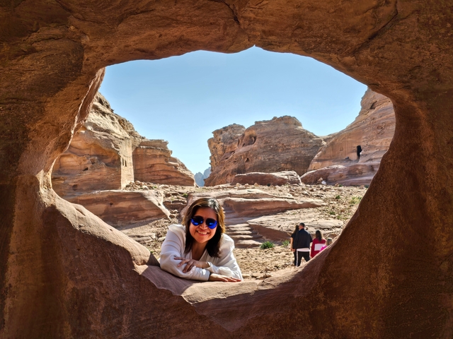 A person posed in a rock formation with a scenic view